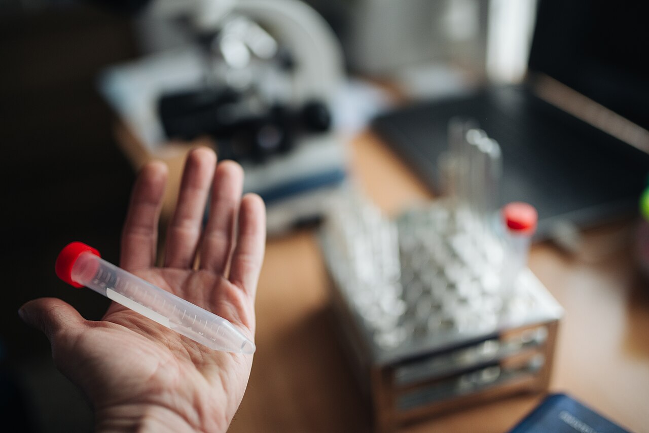 Tangan memegang tabung sampel di ruang laboratorium