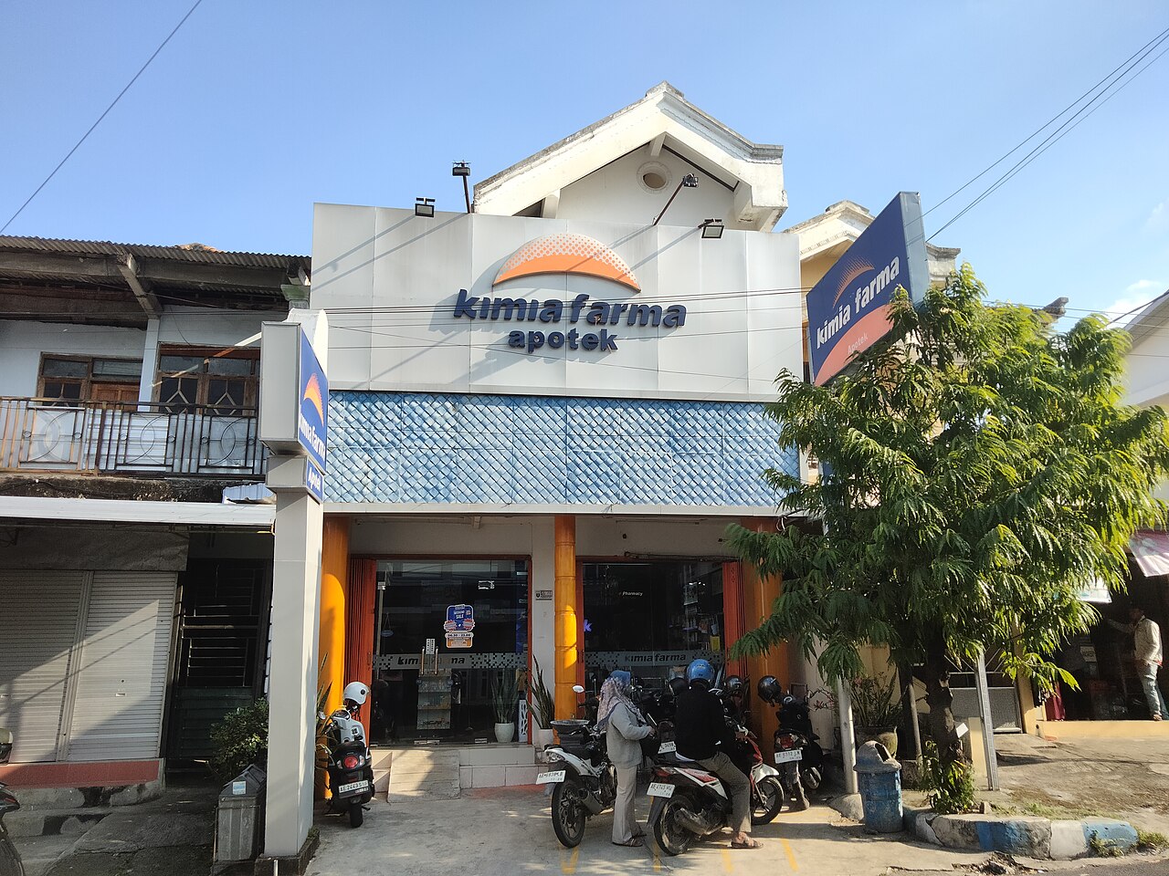 Bagian depan apotek dengan papan nama di tepi jalan