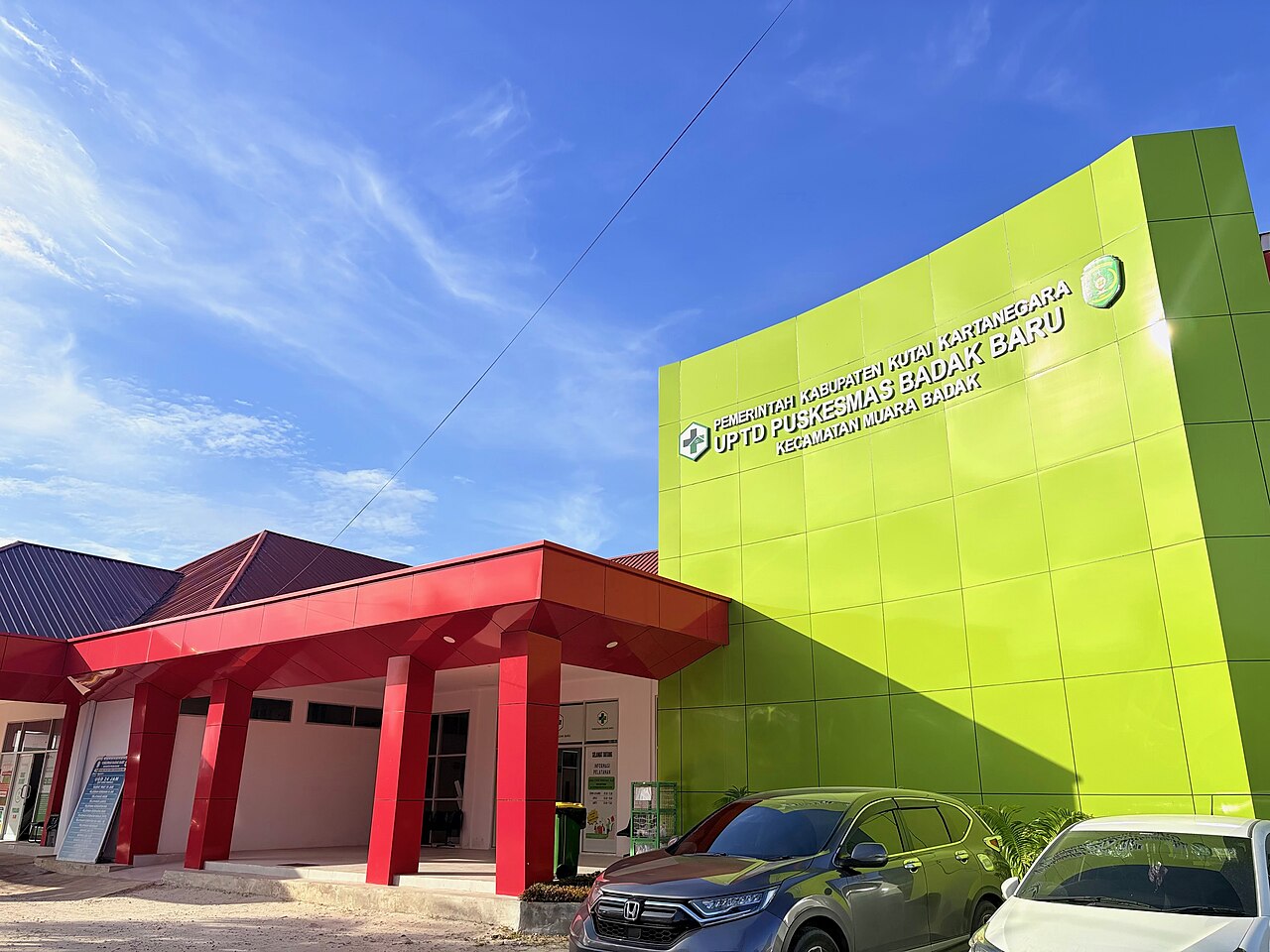 Gedung puskesmas berwarna hijau dengan papan nama besar