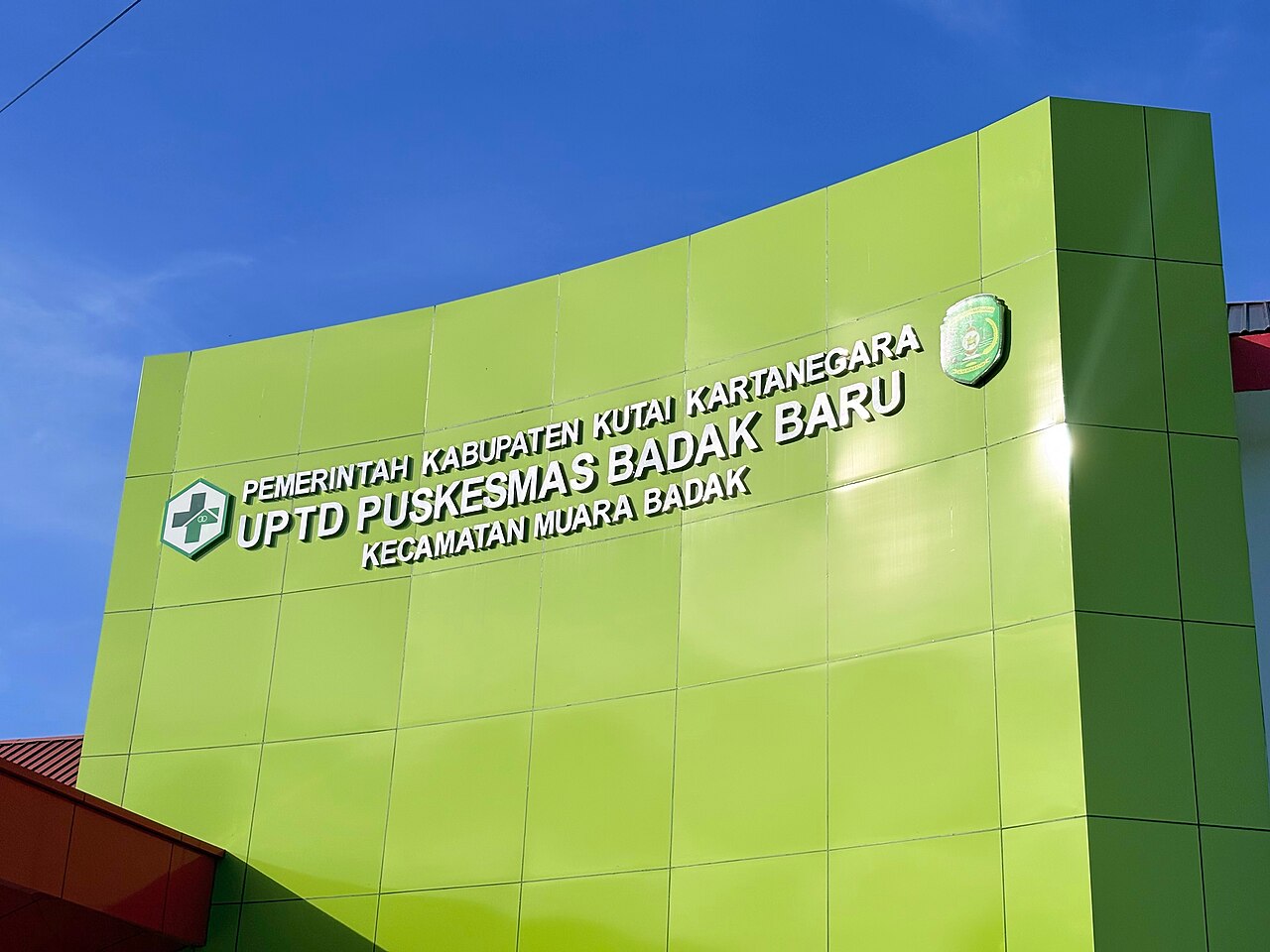 Gedung puskesmas berdinding hijau di bawah langit cerah