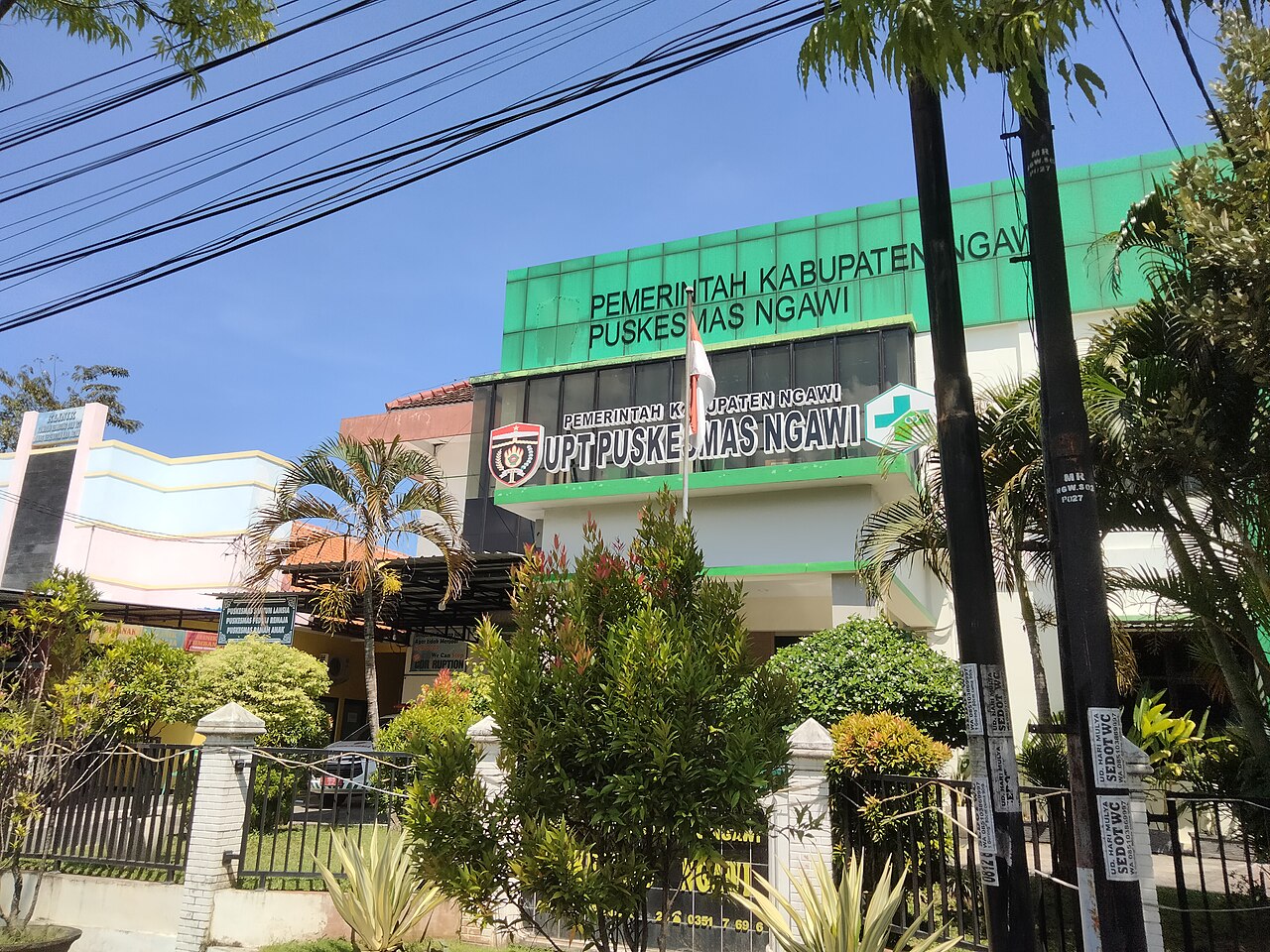 Papan nama puskesmas berwarna hijau di tepi jalan